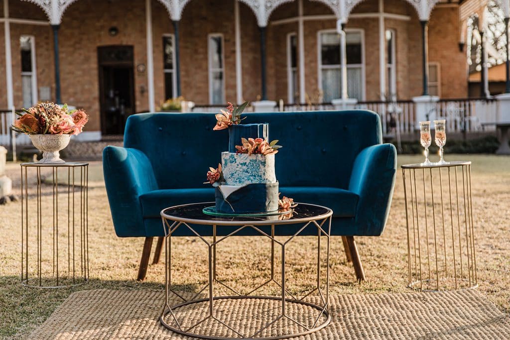 Blue couch with glass and gold coffee table and blue wedding cake