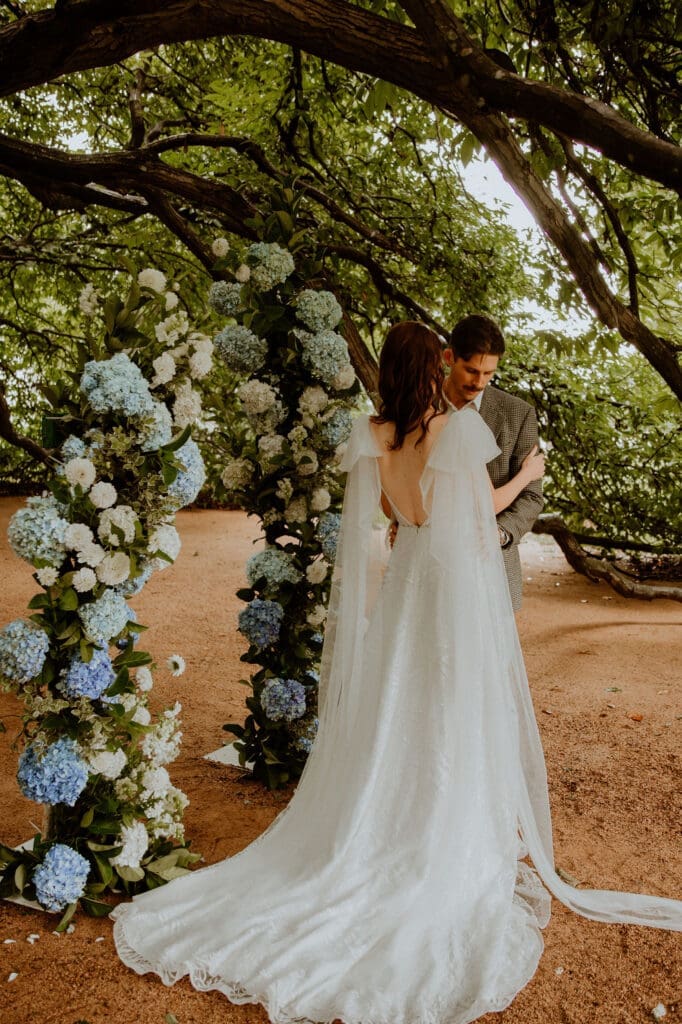 Bride and groom standing under chestnut tree before round floral arch