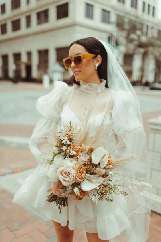 Bride wearing short dress with puff sleeves and sunglasses