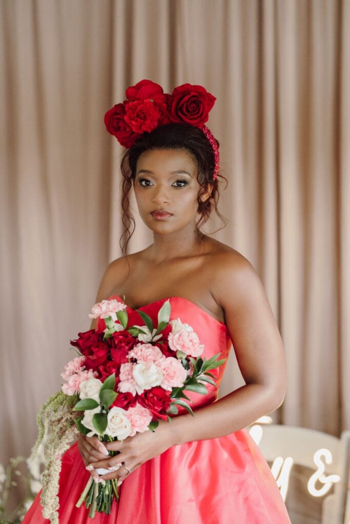 Fashion show model wearing a red wedding dress with red rose crown