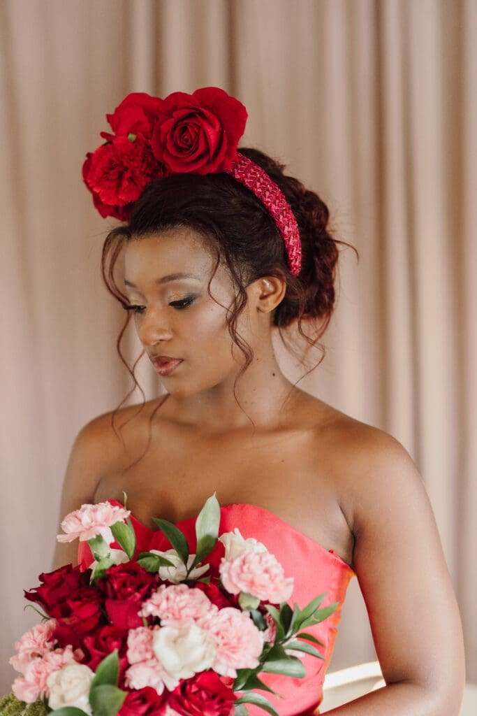 Fashion show model in red wedding dress with red rose headband.
