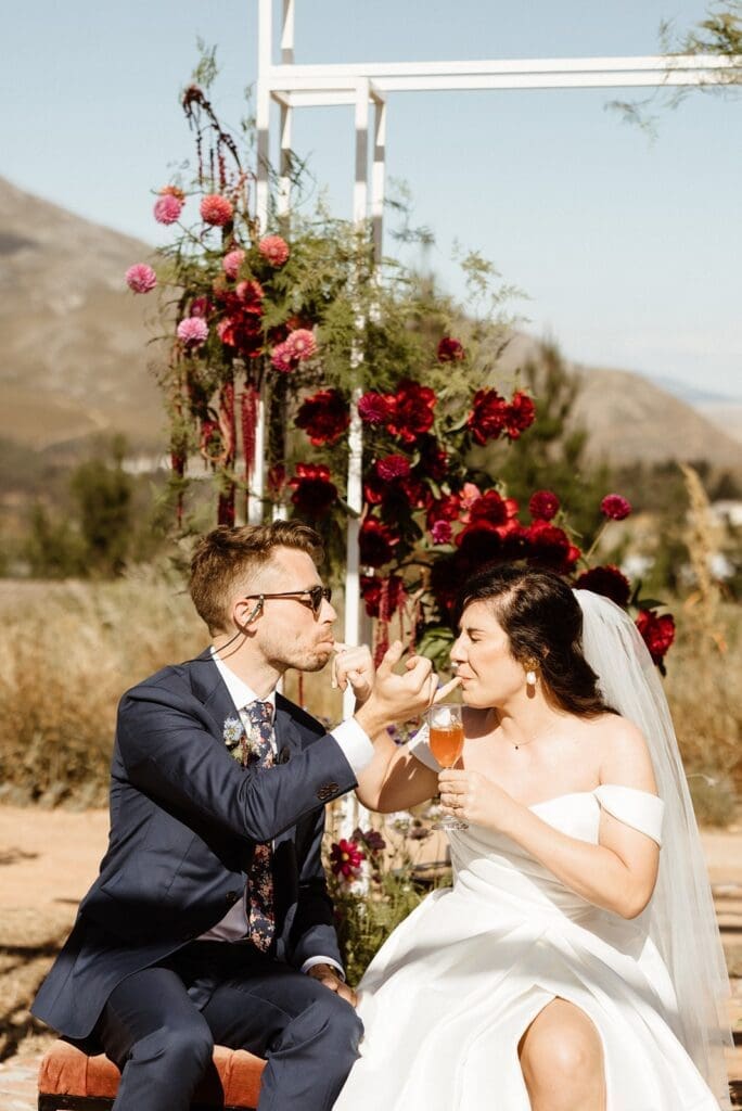 Bride and groom sucking each others pinky dipped in a beverage during custom ceremony
