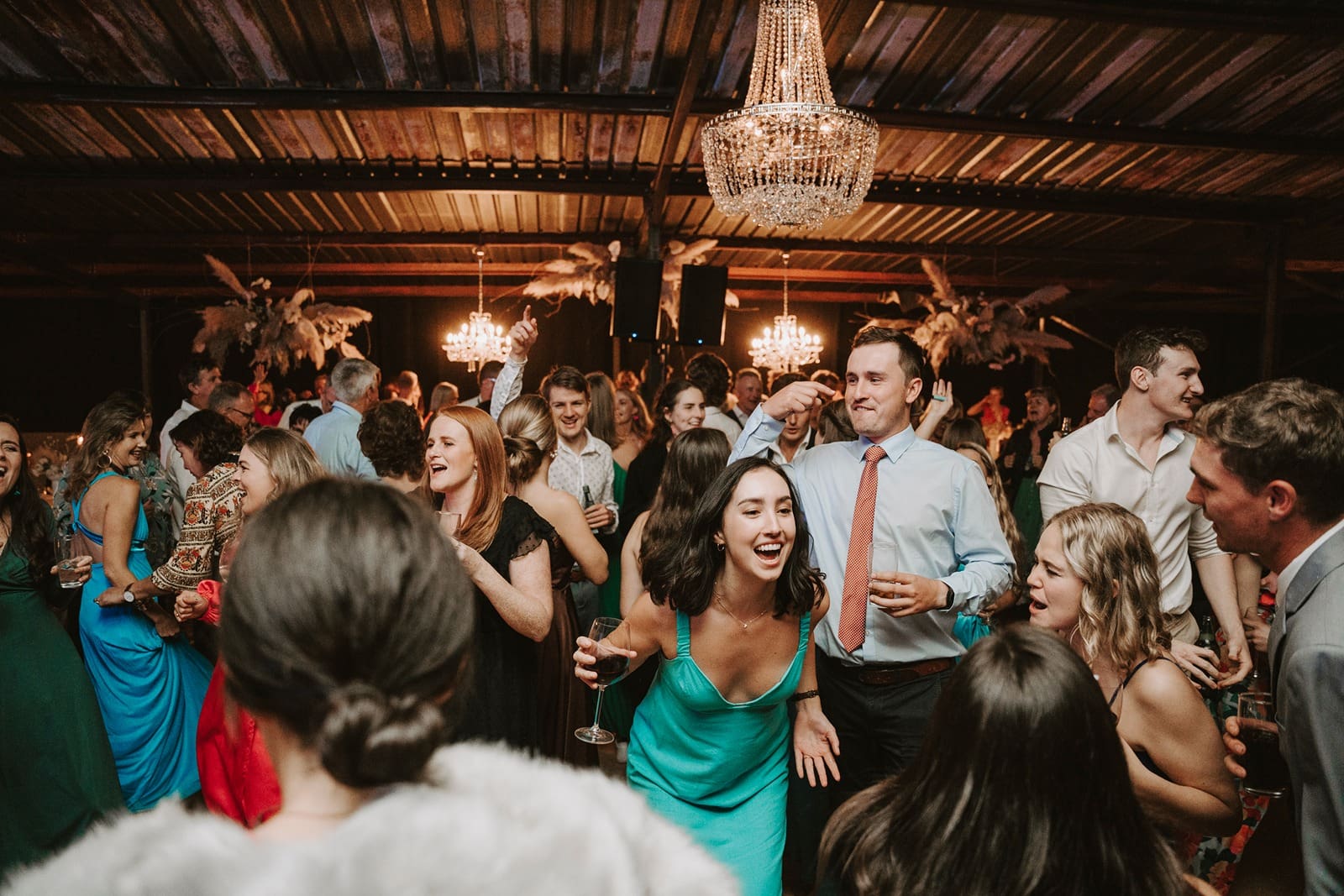 Festive dance floor during wedding reception under beautiful chandelier