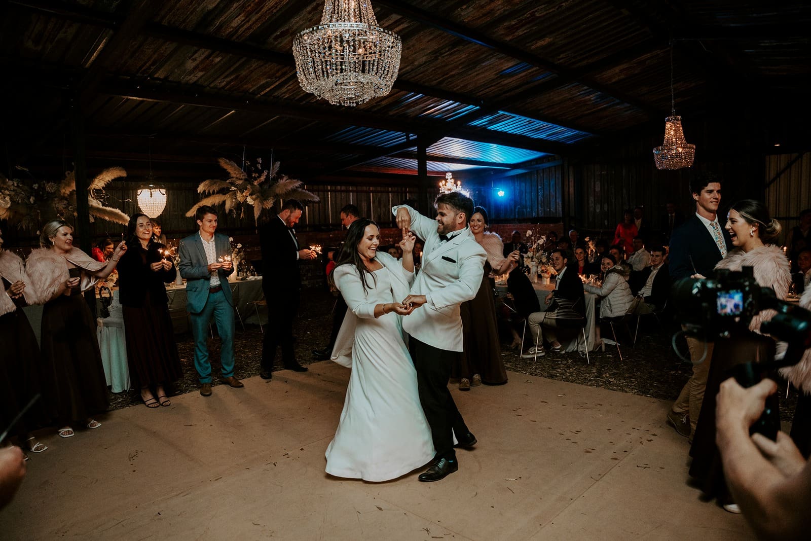 Bride and groom dancing together during wedding ceremony beneath chandelier