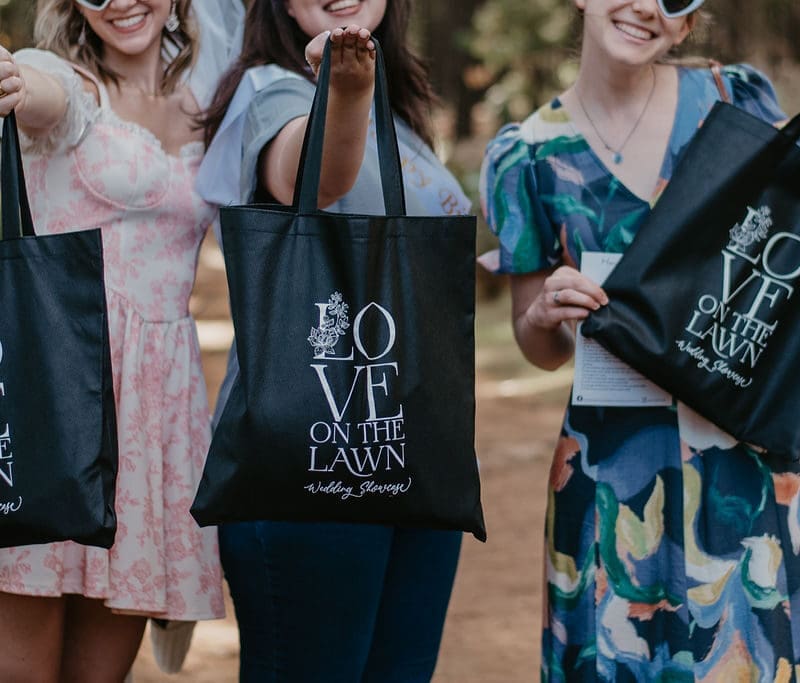 Guests at Love on the Lawn showing off their black goodie bags.