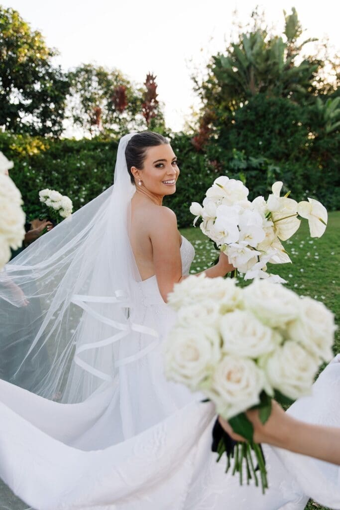 Bride looking over shoulder with white bouquet of flowers
