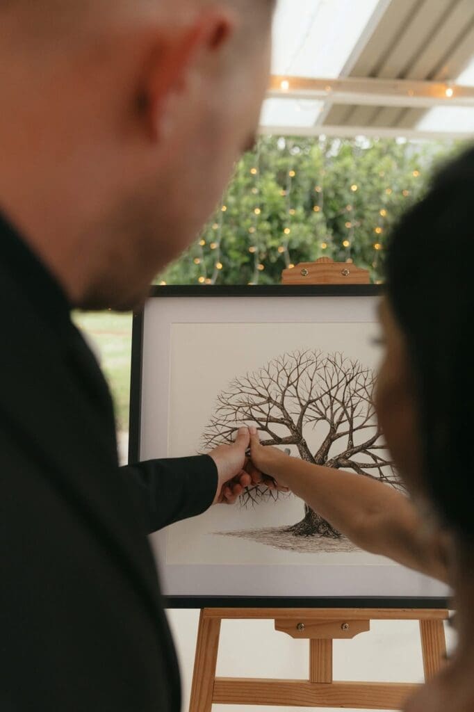 Bride and groom placing their inked fingerprints on their personalized wedding guest book done by Fingerprint Trees.