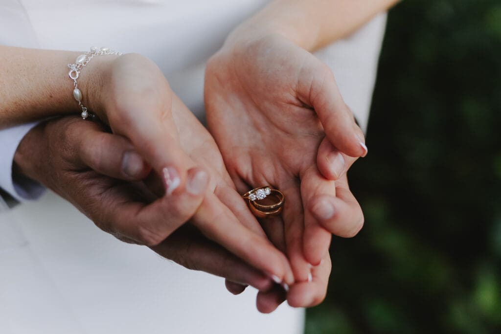 Bride and groom's palms up holding wedding rings