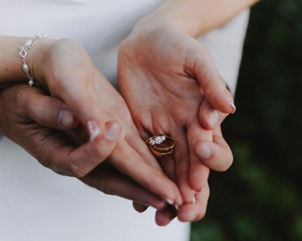 Bride and groom's palms up holding wedding rings