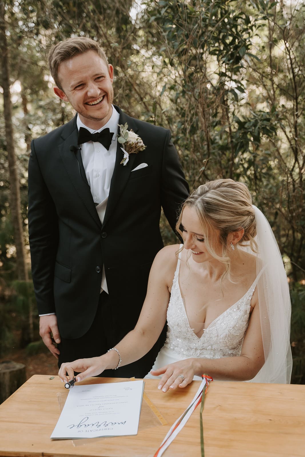 Bride signing marriage contract with groom standing behind her