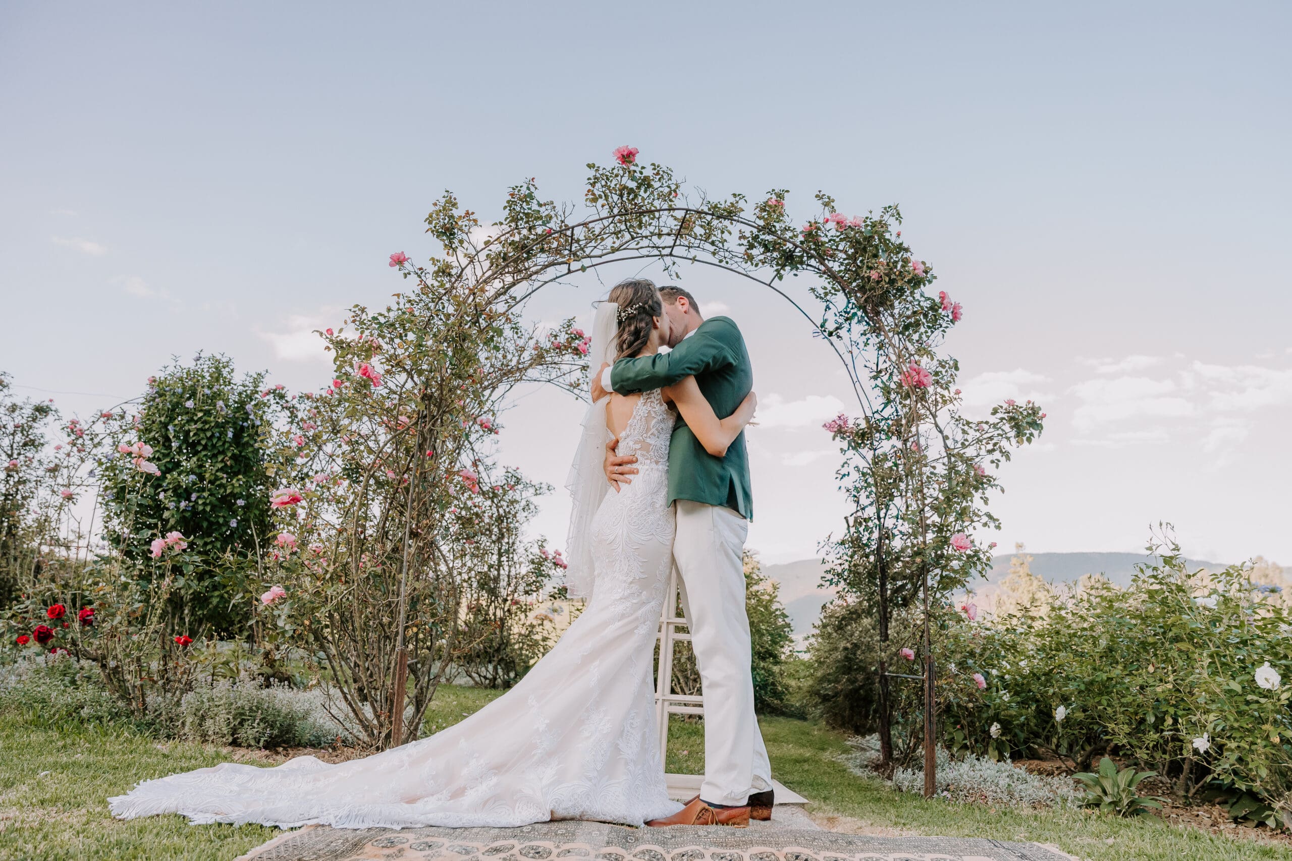Bride and groom kissing infront of floral arch at Weltevreden Manor Wedding Venue
