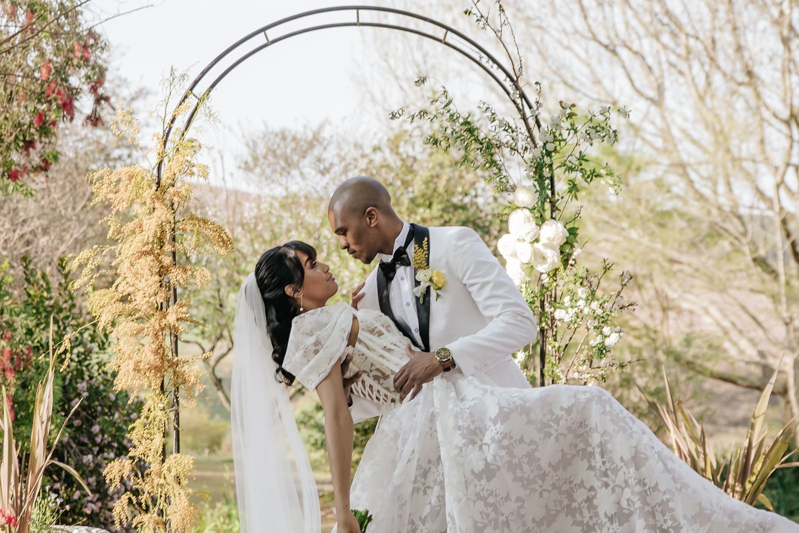 Groom dipping the bride in front of arch at Glen Eden Lodge